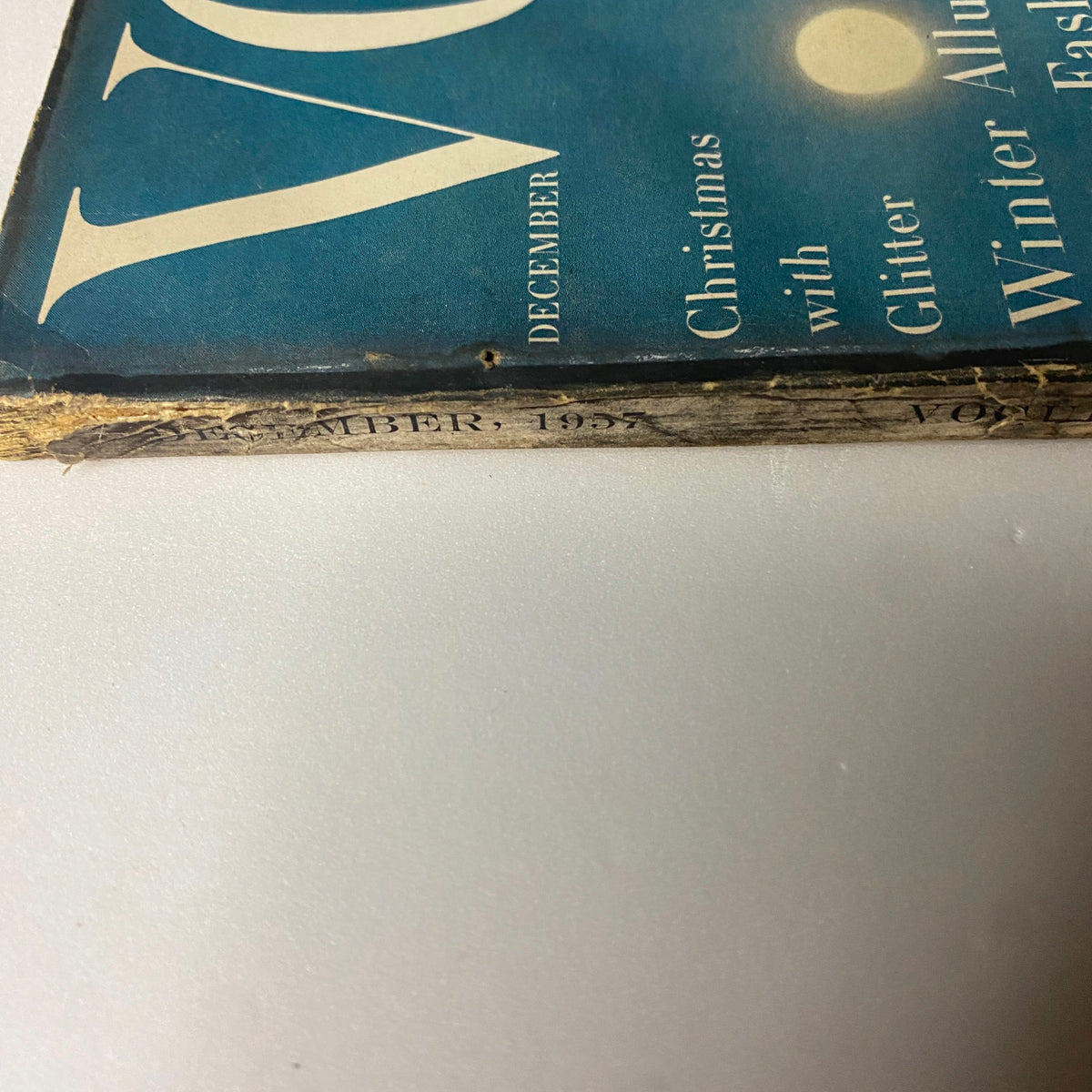 Detailed view of the spine of Vogue Magazine December 1957 Gyongyi Armstrong Cover by Karen Radkai, showing the magazine's vintage features and publication date.
