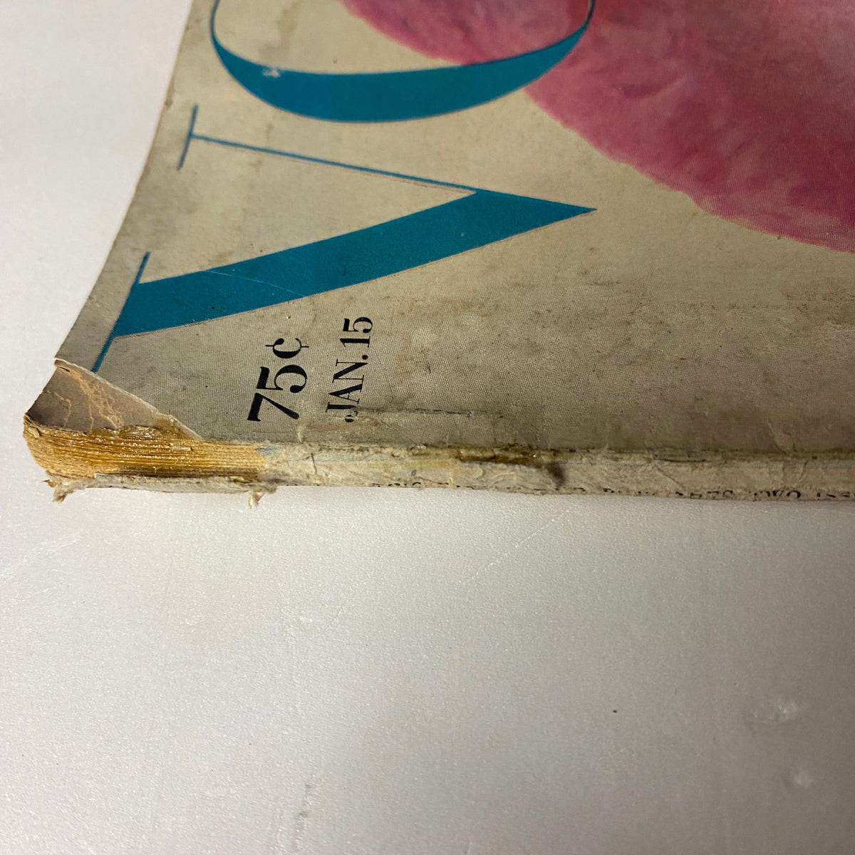 Close-up view of the spine of Vogue Magazine January 15, 1964, showing vintage wear, indicating its preservation as an original item.