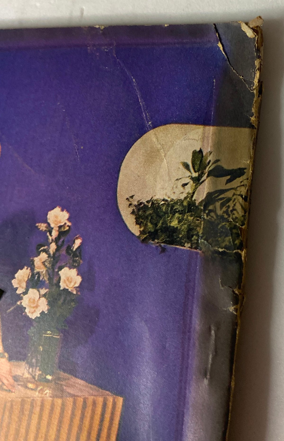 Close-up of the cover corner of Vogue Magazine January 1, 1944, showing minor wear and tear, indicating its vintage condition, with floral designs in the background.