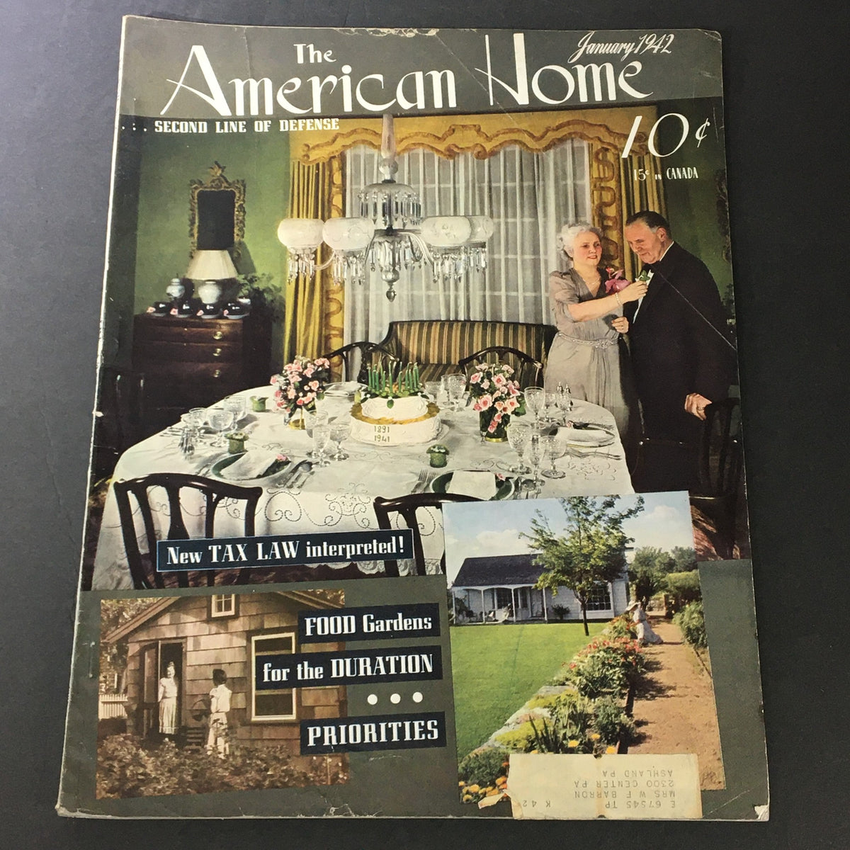 Cover of VTG The American Home January 1942 illustrating wartime dining, with a table set for a meal, featuring a couple engaged in conversation. The magazine highlights topics like food gardens, priorities during the war, and new tax laws.