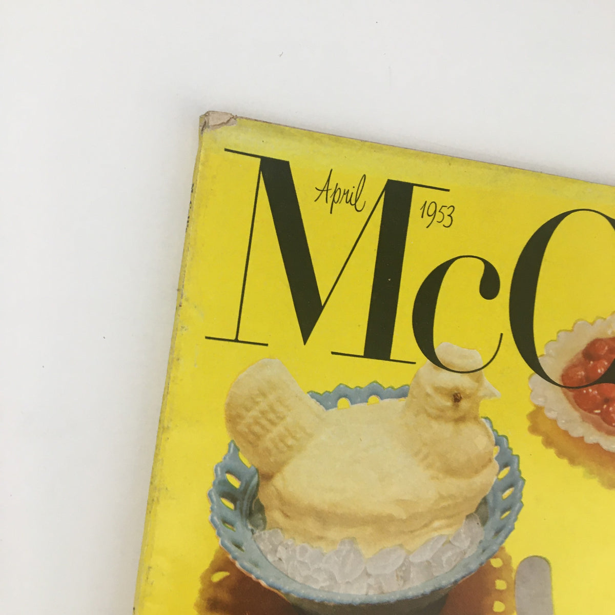Close-up of the upper section of the cover of VTG McCall's Magazine April 1953 with the title and a decorative butter chick dessert, emphasizing the magazine's nostalgic vintage appeal.