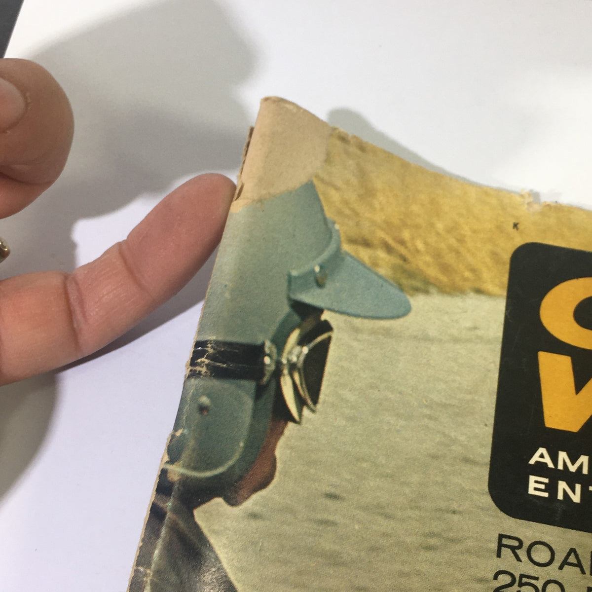 Close-up view of the corner of Cycle World Magazine August 1965 showing the iconic logo and a vintage motorcycle enthusiast in a helmet.