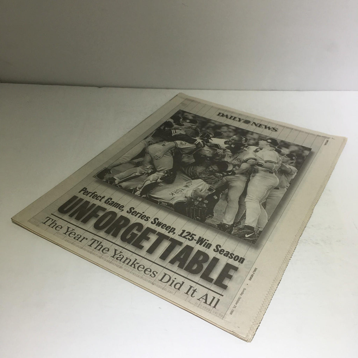 Front cover of the NY Daily News: 10/25/98 Perfect Game, Series Sweep, 125-Win Season, displaying the headline 'UNFORGETTABLE' with a historic image of jubilant Yankees players celebrating.