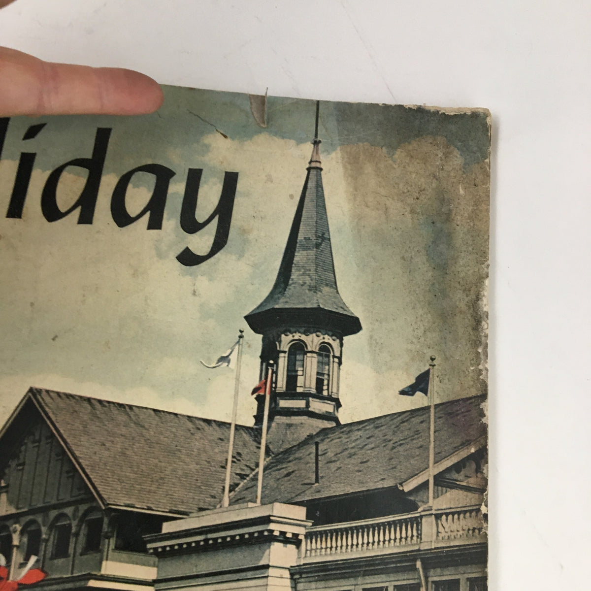 Close-up of the top section of the Holiday Magazine May 1946 cover, showing the title 'Holiday' and the architecture of a building, complete with a spire and flags, emphasizing its vintage appeal.