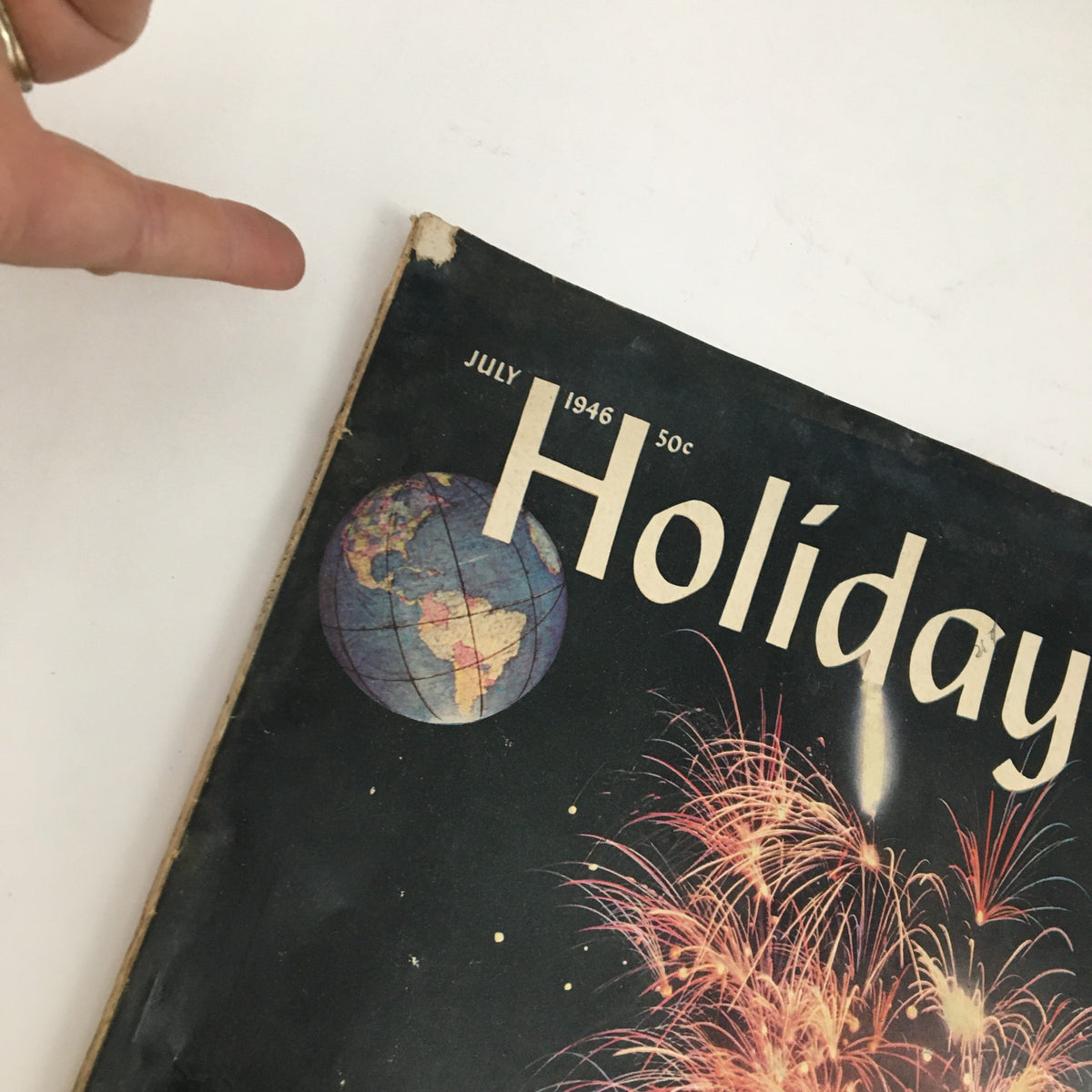 Cover of Holiday Magazine July 1946 depicting the title and a globe with fireworks, showcasing the vintage design and post-war theme.