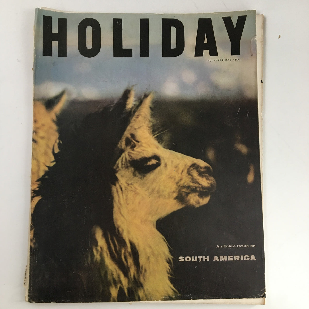 Cover of Holiday Magazine November 1956 featuring a close-up of a llama, highlighting an entire issue on South America. This vintage magazine showcases travel narratives and stunning photography from the mid-20th century.