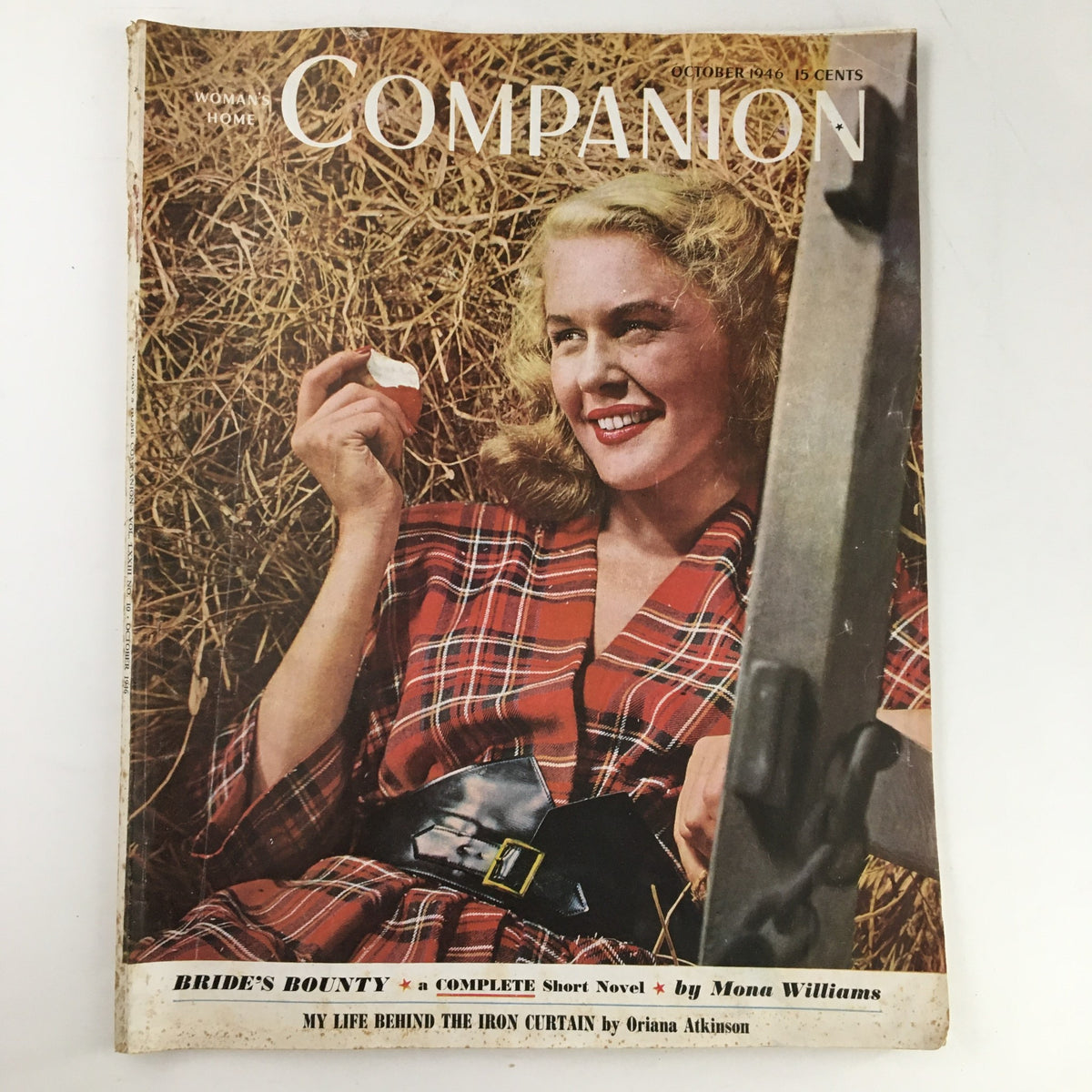 Cover of Woman's Home Companion October 1946 featuring article My Life Behind The Iron Curtain, showcasing a woman in a plaid dress holding a small object amidst hay.