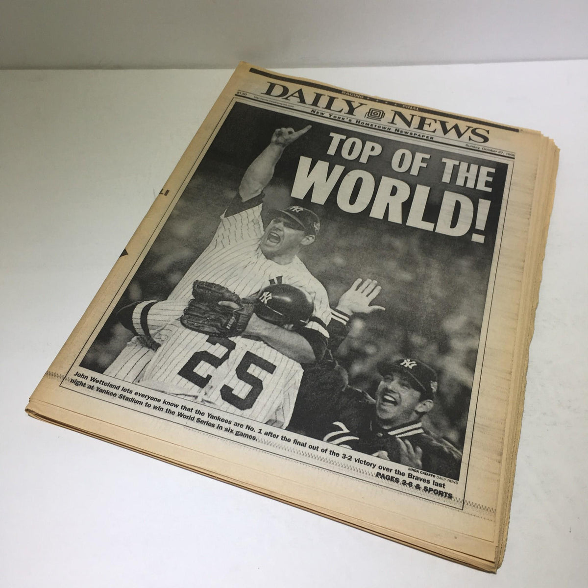 Vintage New York Daily News newspaper from October 27, 1996, featuring the headline 'TOP OF THE WORLD!' celebrating the New York Yankees' success. The image depicts a jubilant scene with players rejoicing, reflecting a significant moment in sports history.