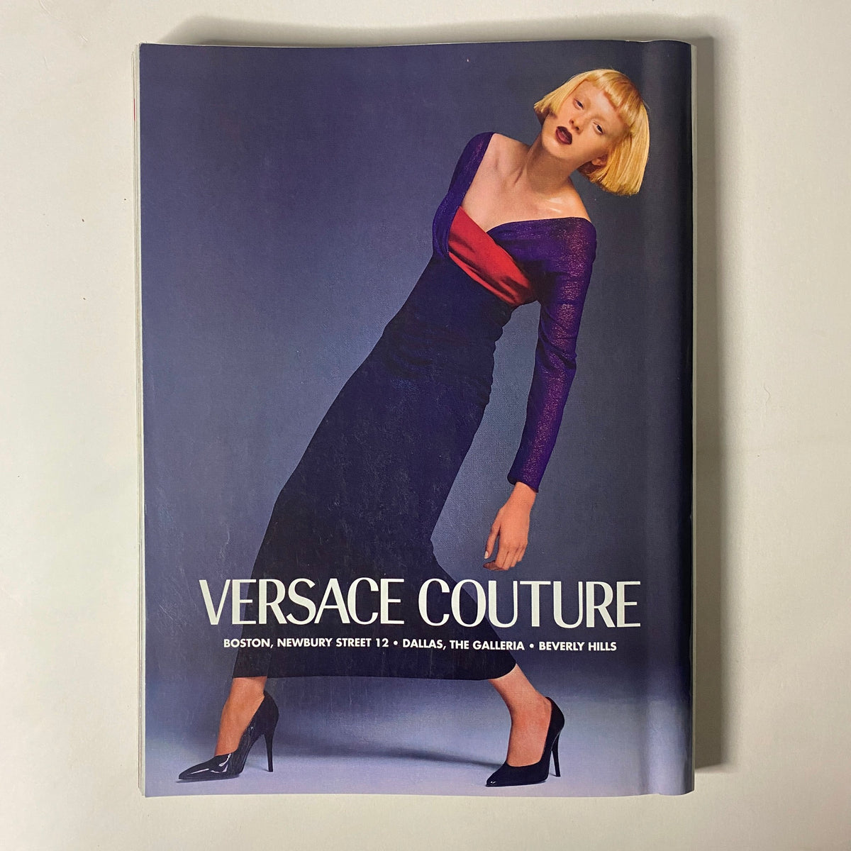 A fashion editorial image presenting a model wearing a purple Versace Couture dress in Vogue Magazine November 1997, featuring Stella Tennant on the cover by Steven Meisel.