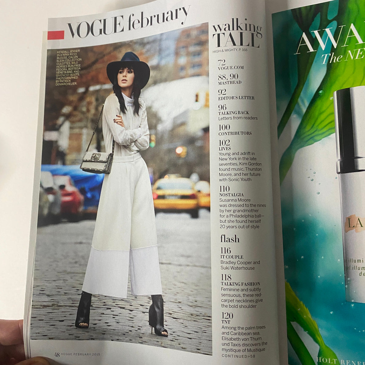 Interior page from Vogue Magazine February 2015 showing a fashion spread with a model in a white outfit and hat, alongside an advertisement for luxury skincare, highlighting topics covered in the issue, such as style and fashion insights.