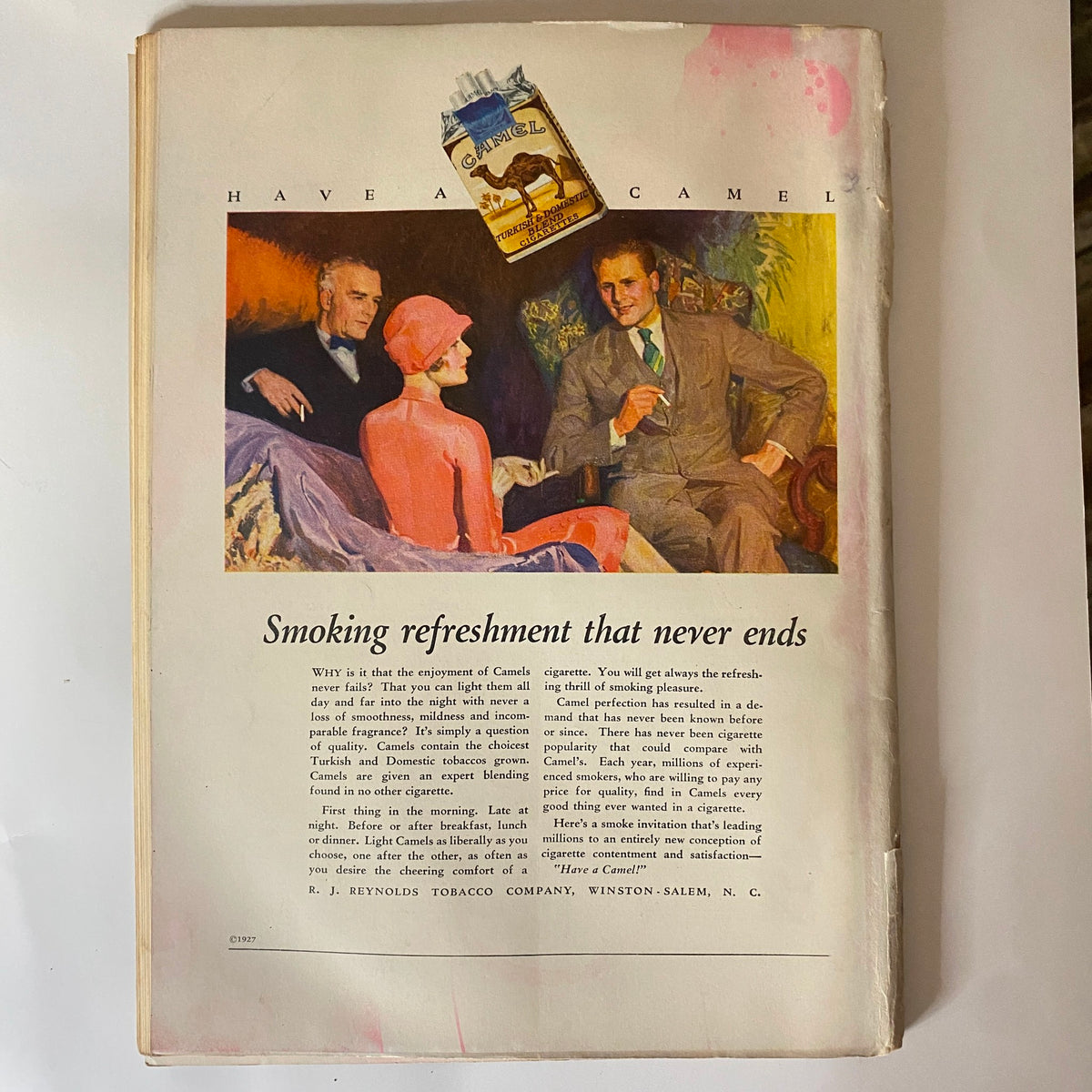 Back cover of The New Yorker Complete Magazine January 29, 1927 featuring an advertisement for Camel cigarettes, showcasing a vibrant illustration of a man and woman in conversation with a third person, emphasizing the theme of 'Smoking refreshment that never ends'.