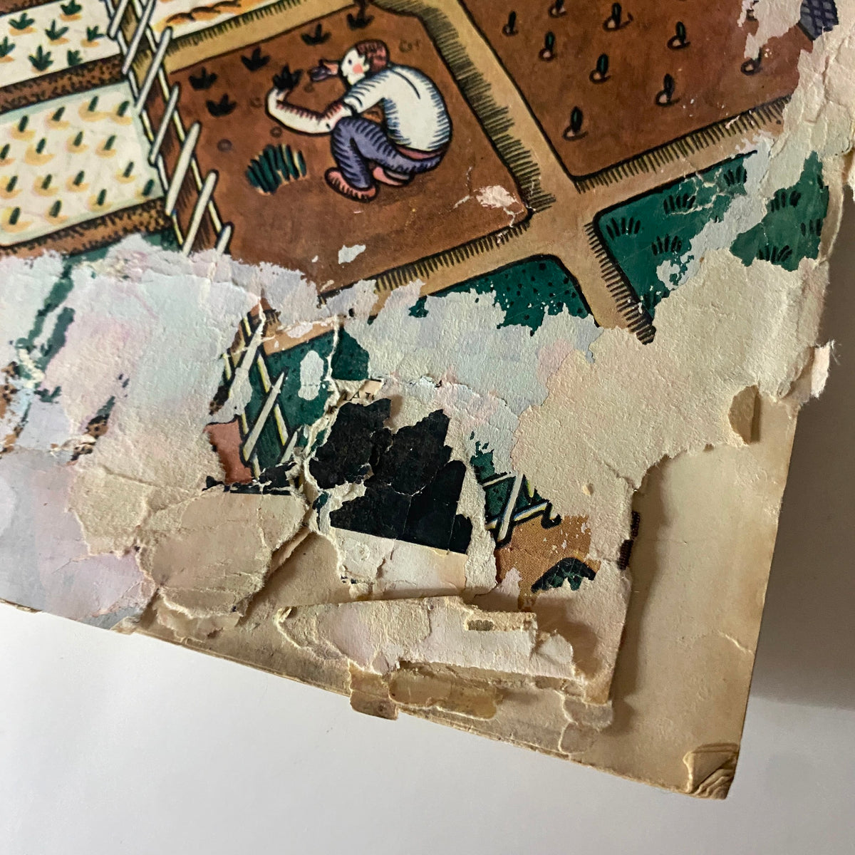 Detailed view of the damaged cover of The New Yorker Complete Magazine - May 7, 1927, highlighting the artistic depiction of farming activities with visible wear.