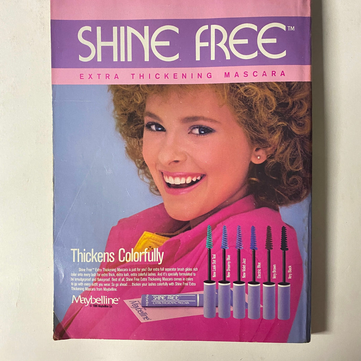 Advertisement for Maybelline's Shine Free Extra Thickening Mascara featured in Seventeen Magazine August 1986, showcasing colorful mascara options next to a model with curly hair.