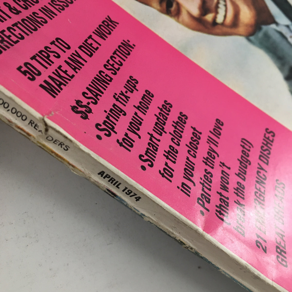Close-up view of the spine of Woman's Day Magazine April 1974, showing details of the issue's advertisements and features, including tips on home fix-ups and spring clothing.