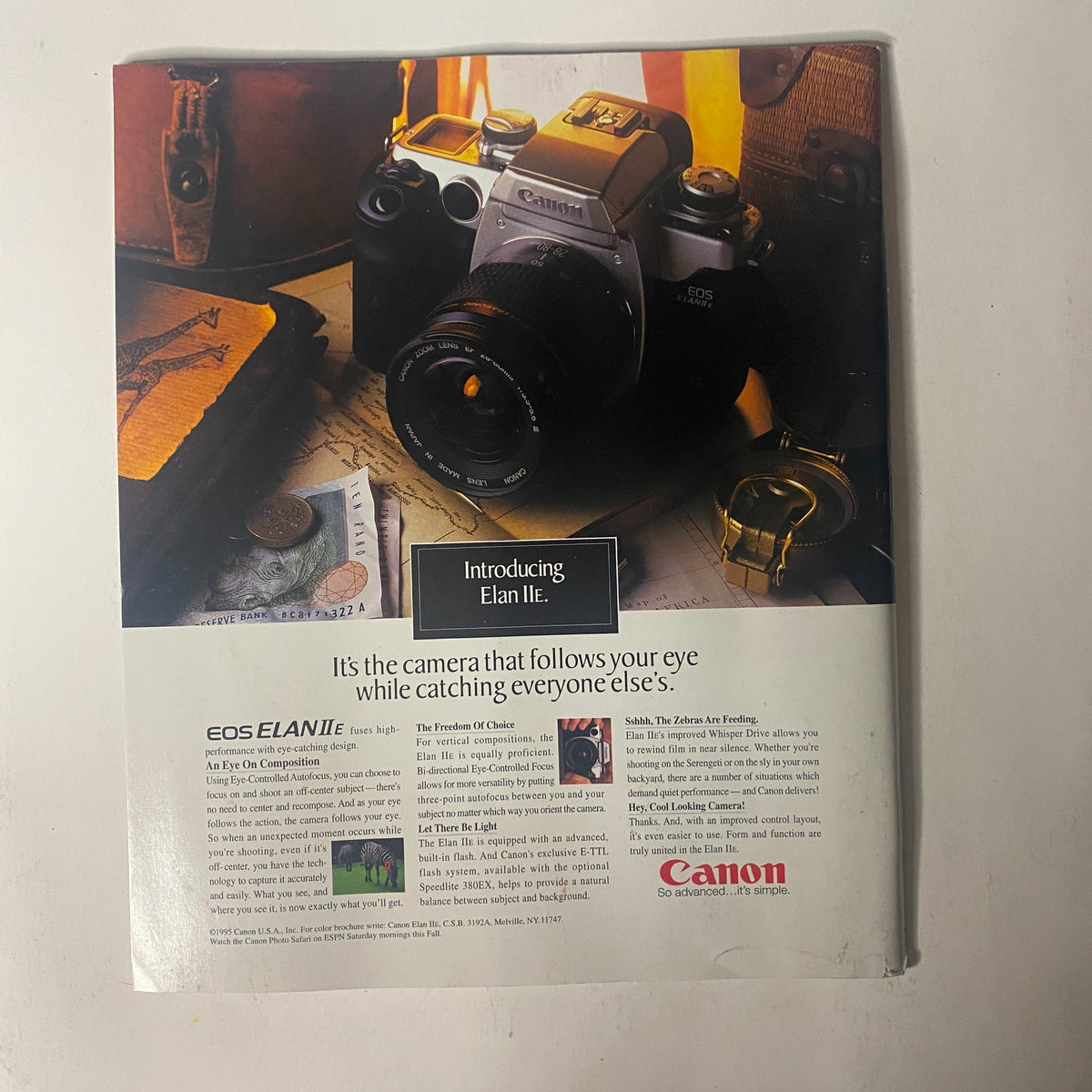 Advertisement for Canon EOS Elan IIe camera showcasing features and offers, complemented by a vintage setting with a desk, notes, and a camera. Related to the Sports Illustrated Magazine 1995 Michael Jordan The Year in Pictures.