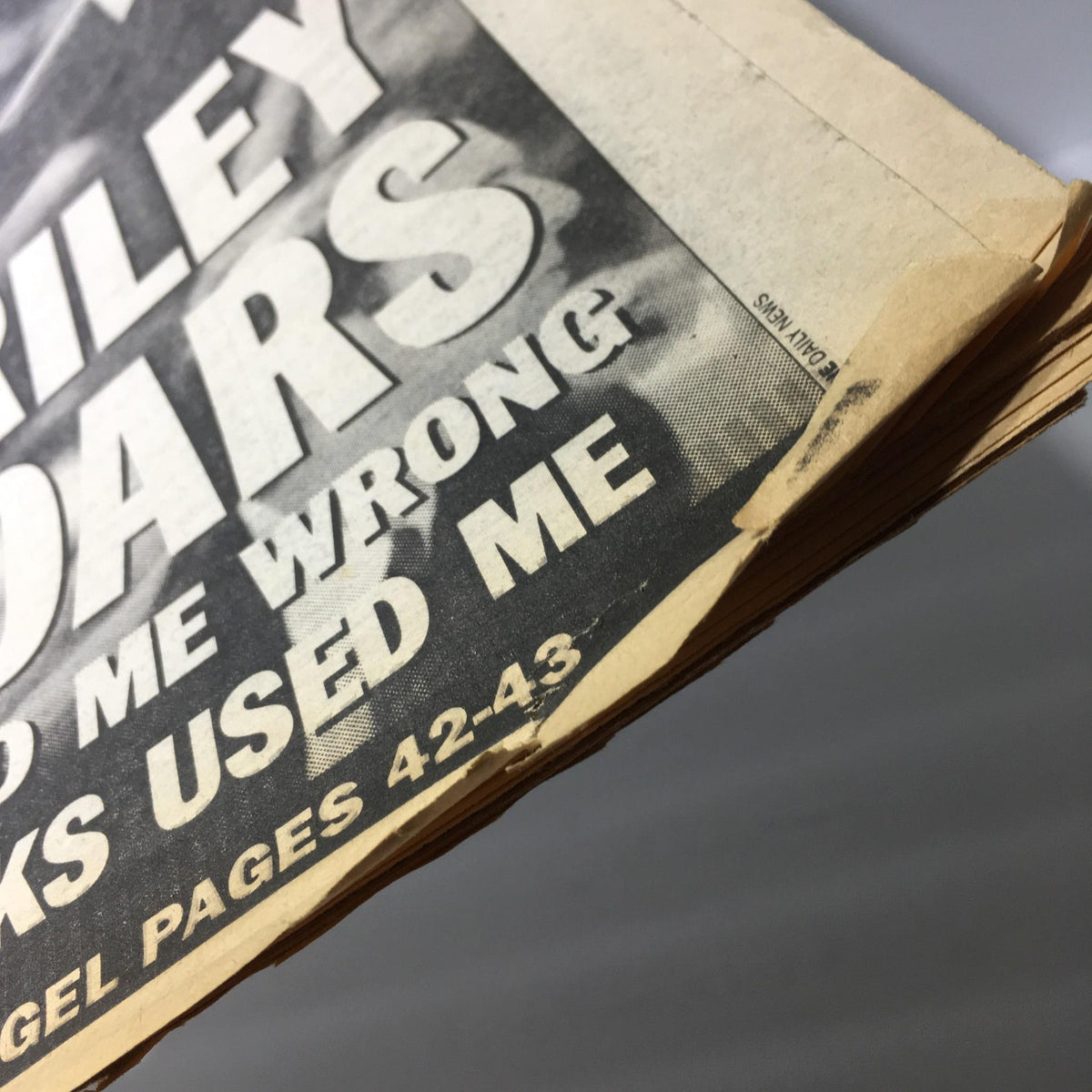 Detailed view of the edge of the NY Daily News, showing the headline 'Riley Roars' and part of the text that mentions 'THE KNICKS USED ME,' highlighting the interview's dramatic tone.