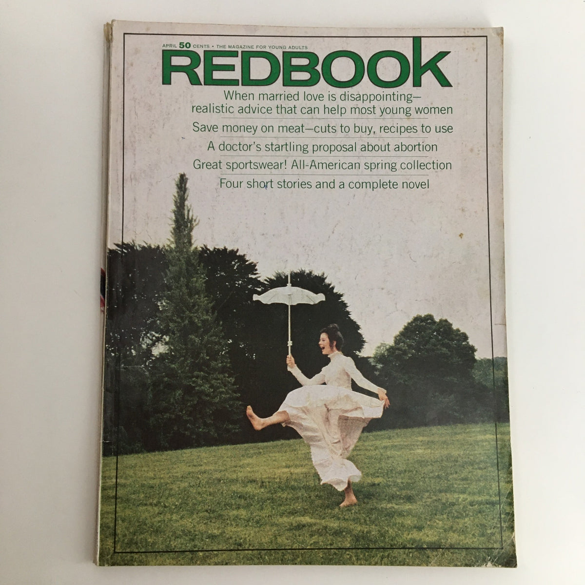 Cover of Redbook Magazine April 1970, Vol. 134 #6, featuring a photograph of a smiling woman in a flowing dress, holding an umbrella, set against a lush green landscape.