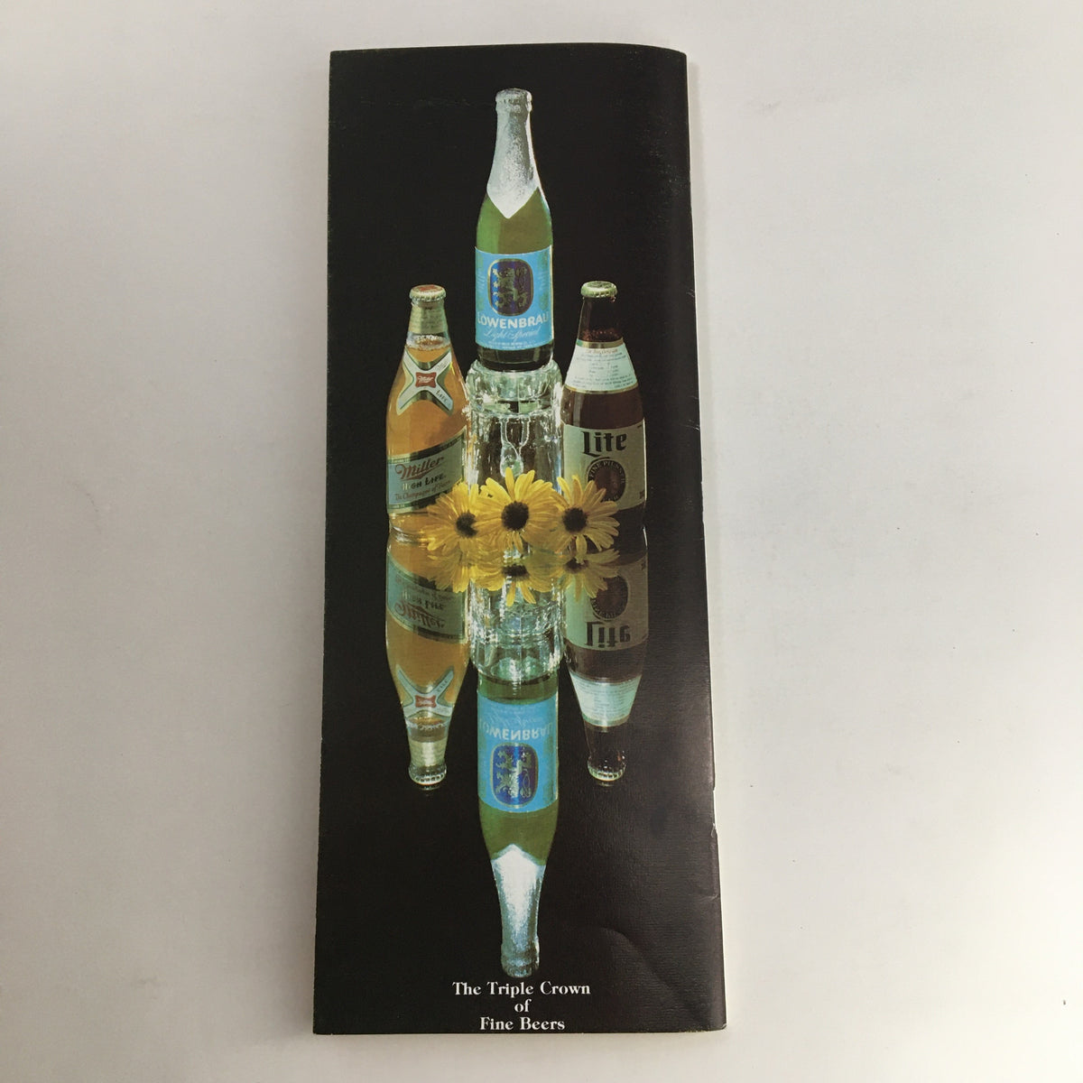 1986 Pimlico Race Course The Preakness Official Souvenir Program showcasing a reflective image of various beer bottles and flowers, symbolizing the festive atmosphere of horse racing events.