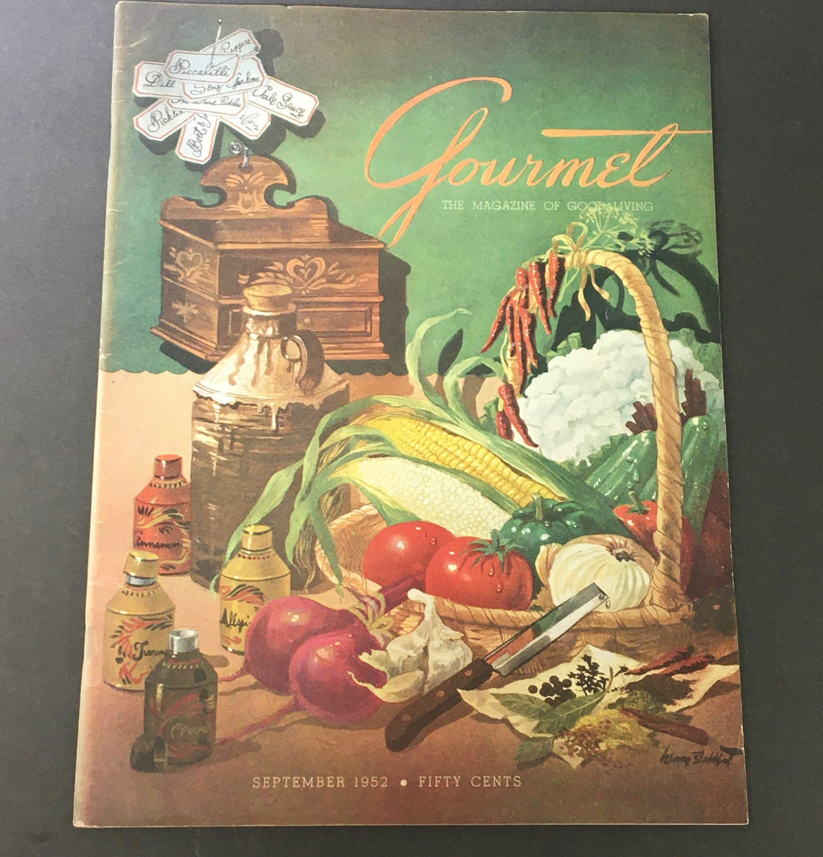 VTG Gourmet: The Magazine of Good Living September 1952 cover featuring a vibrant illustration of ingredients like vegetables, fruits, and cooking items, reflecting mid-century dining and the theme of a backyard Luau.