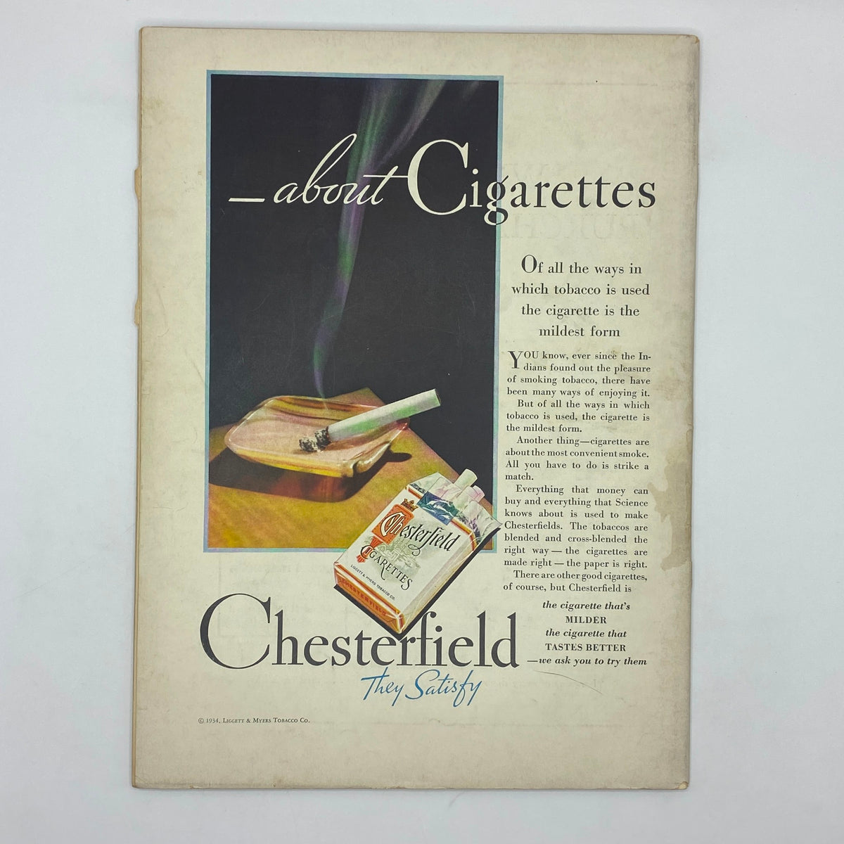 Historical Chesterfield cigarette advertisement depicting a cigarette and an ashtray with smoke, conveying the milder taste of Chesterfield cigarettes. This ad is part of The New Yorker Complete Magazine February 10, 1934.