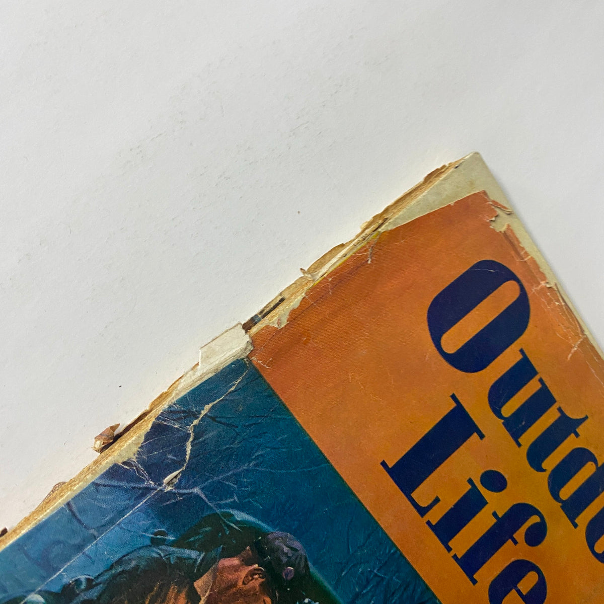 Close-up view of the cover corner of Outdoor Life Magazine March 1947 featuring a vintage design by Ralph Crosby Smith, showing wear and tear on the edges.