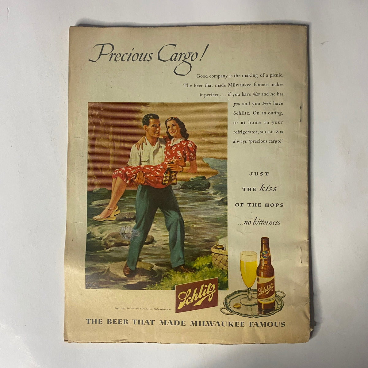 Vintage promotional advertisement for Schlitz beer, titled 'Precious Cargo'. The design features a couple enjoying a relaxed moment at a scenic location, highlighting the tagline 'Good company is the making of a drink.' This image is from a vintage context, appealing to collectors of classic advertisements.