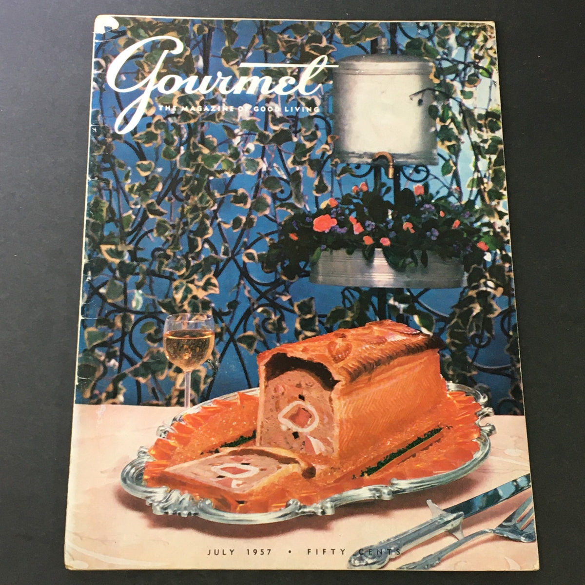 Cover of VTG Gourmet The Magazine of Good Living July 1957 featuring a decorative cake on a silver platter with a glass of wine, embodying the essence of Straw Hat Suppers.