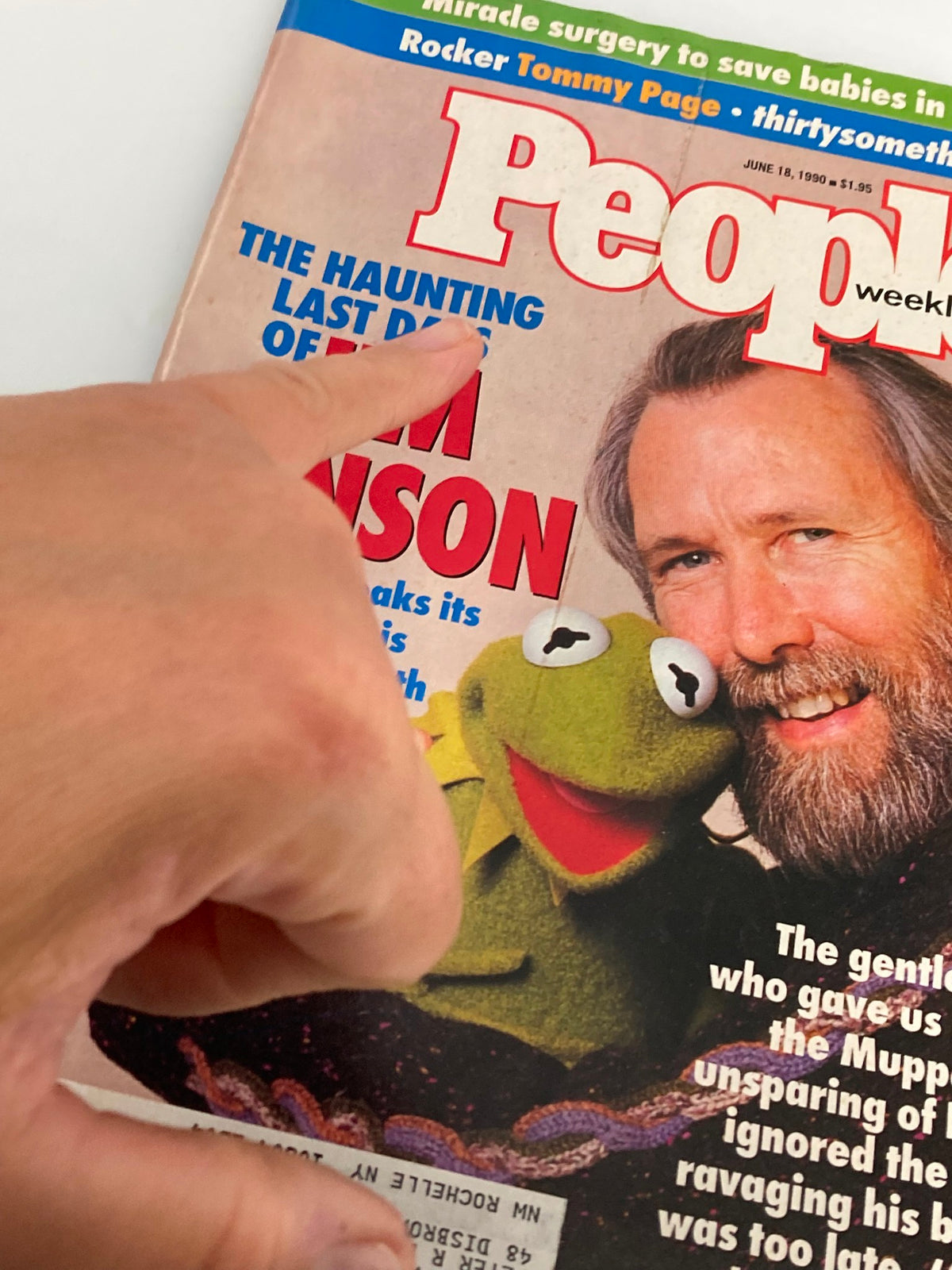 Close-up of the People Weekly Magazine cover from June 18, 1990, highlighting the title 'The Haunting Last Days of Jim Henson' with a hand pointing at the text.