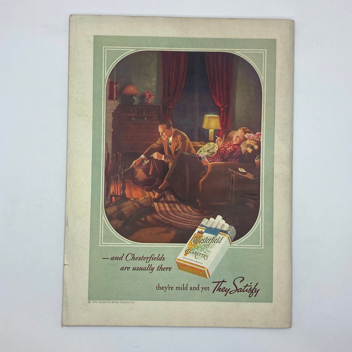 Classic advertisement for Chesterfield cigarettes, depicting a cozy living room scene. The ad features a man and woman relaxing by a fireplace. This image is from The New Yorker Complete Magazine April 14, 1936.
