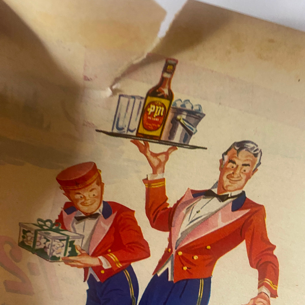Close-up of a vintage advertisement showing a waiter holding a bottle of PM liquor and a tray of drinks, part of the artwork related to Field & Stream Magazine May 1948 issue titled 'Refuge Payoff' by Harold Titus.