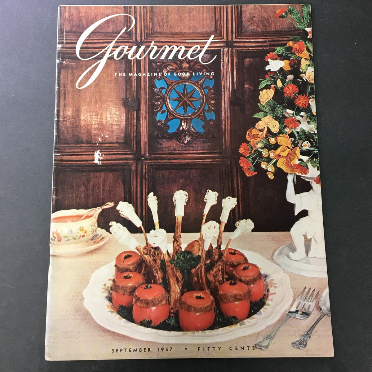 VTG Gourmet Magazine September 1957 cover featuring a decorative table setting with a dish of lamb chops and stuffed tomatoes, showcasing the theme 'Land of Mamaliga'.