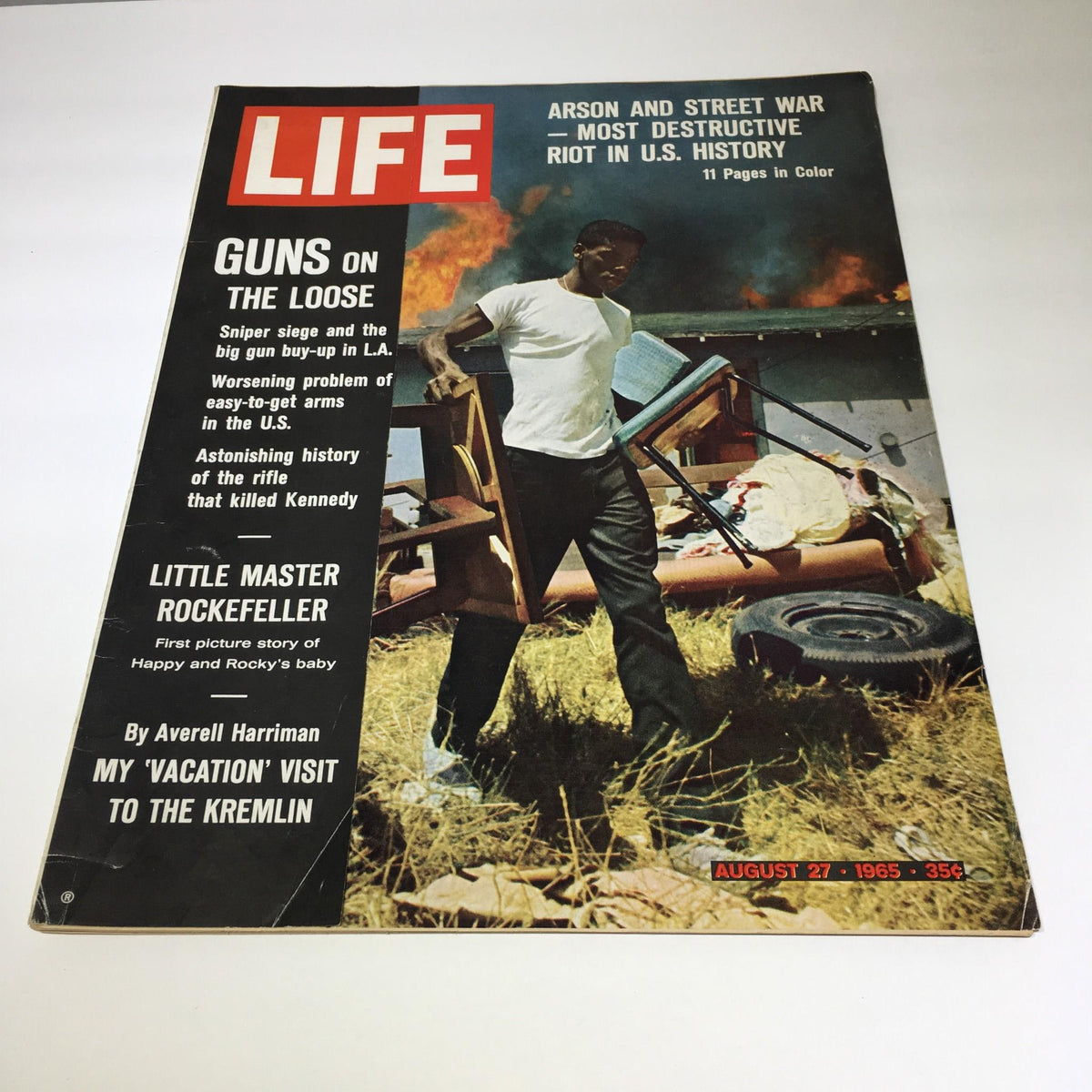 Vintage Life Magazine cover from August 27, 1965, featuring the title 'Arson and Street War - Most Destructive Riot in U.S. History'. The cover illustrates a man carrying chairs amid a chaotic scene of fire, emphasizing the societal challenges of the 1960s.