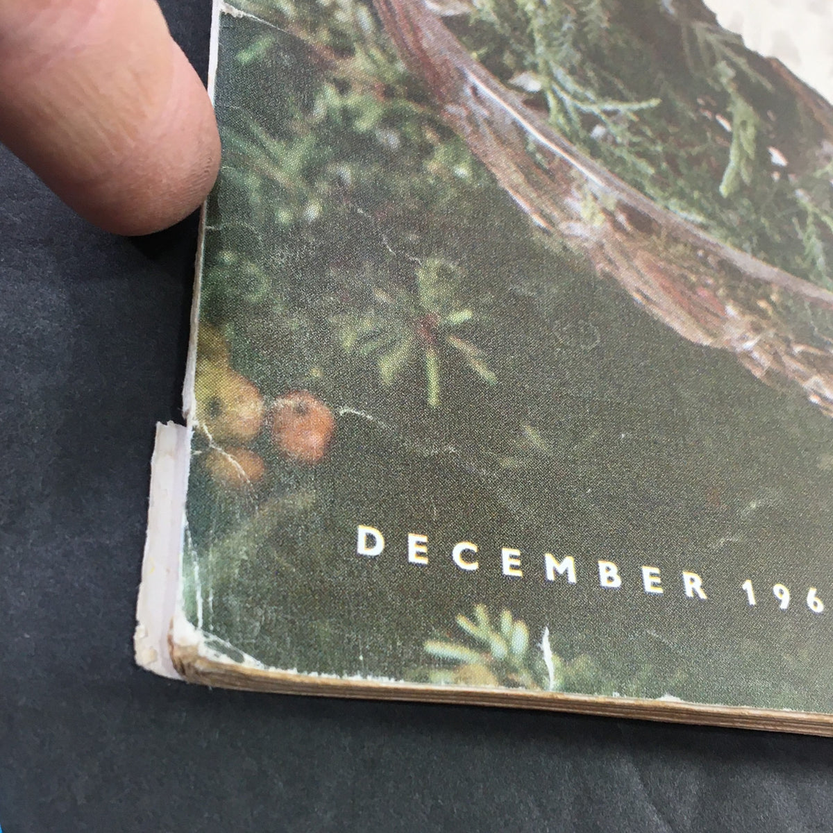 Close-up view showcasing the wear and tear on the spine of the VTG Gourmet Magazine December 1961, indicating vintage character.
