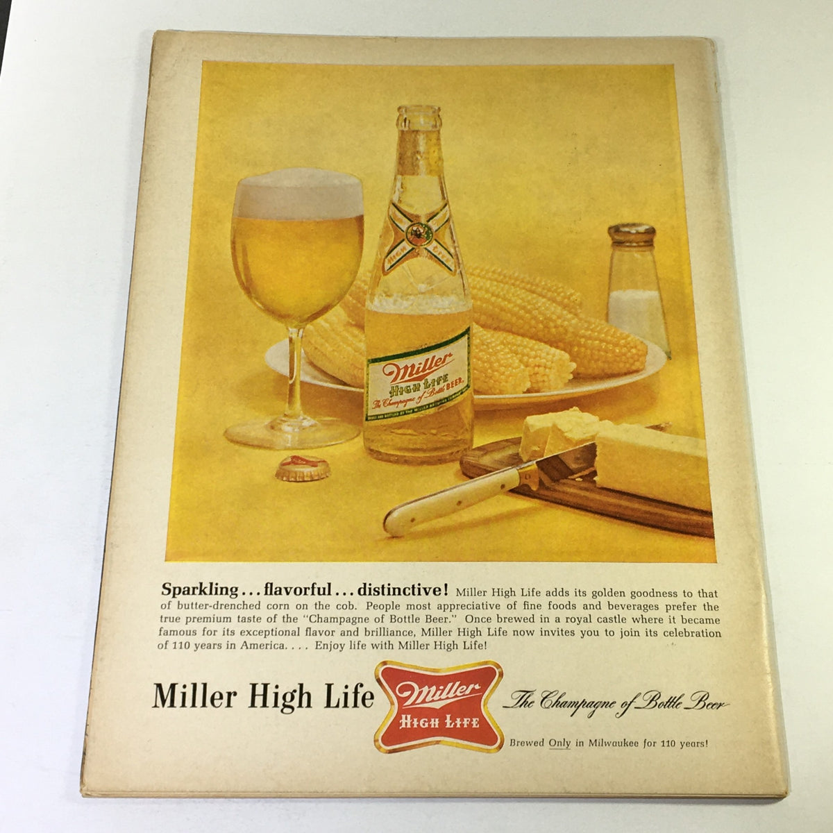 Back cover of VTG Gourmet The Magazine of Good Living, August 1965, showcasing a vintage advertisement for Miller High Life beer, with a bottle, glass, and accompanying food items against a bright yellow background.