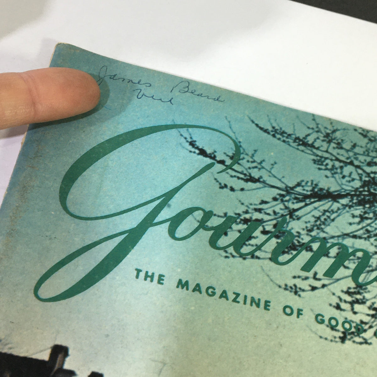 Close-up of the top left corner of the VTG Gourmet: The Magazine of Good Living August 1969 cover, displaying the handwritten name 'James Beard' and the magazine title.