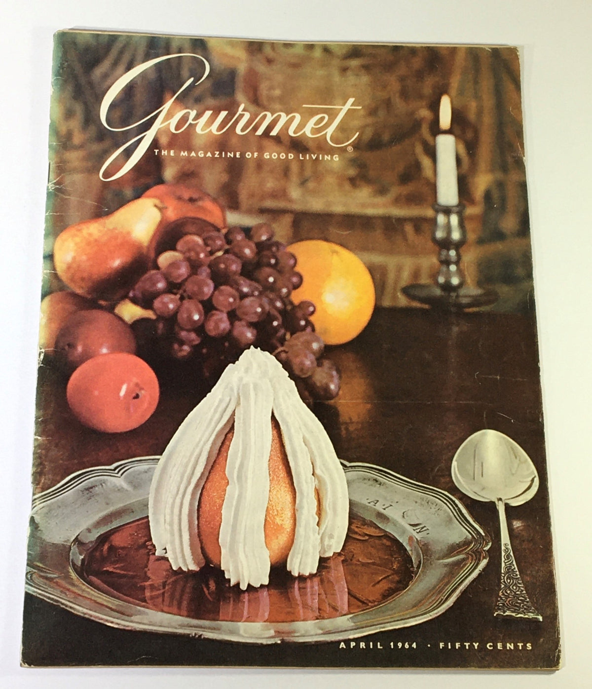 VTG Gourmet The Magazine of Good Living April 1964 cover featuring a dessert presentation on a silver plate, with fruits in the background and a candle in the scene.