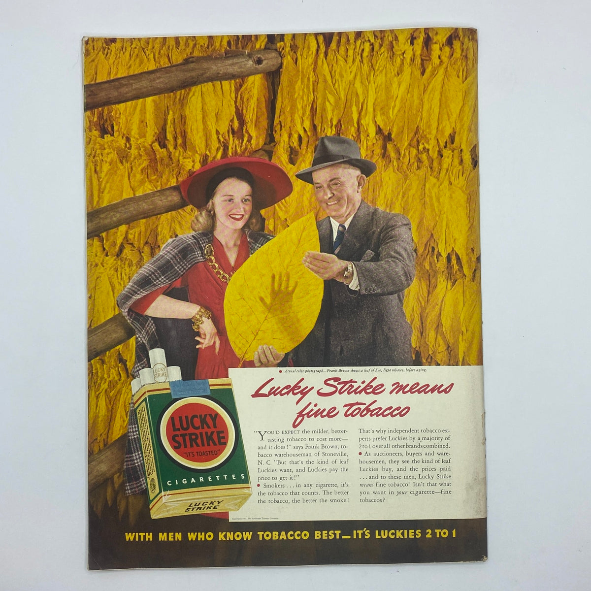 Advertisement for Lucky Strike cigarettes from The New Yorker Complete Magazine November 15, 1941, featuring a woman and a man holding a large tobacco leaf with the Lucky Strike packaging prominently displayed.