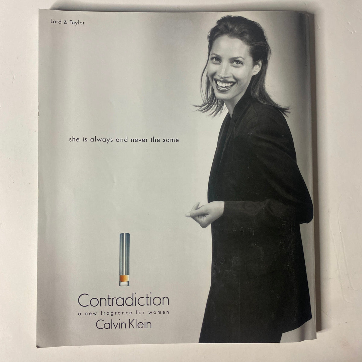 Advertisement for Calvin Klein's Contradiction fragrance featuring a smiling model in a black outfit, part of the December 1997 issue of Martha Stewart Living Magazine.