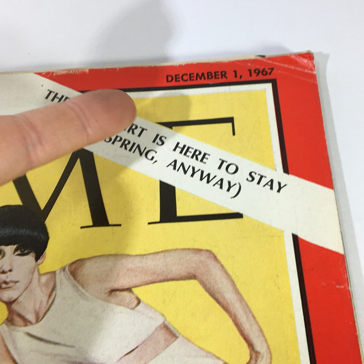 Side view of the Vintage Time Magazine cover, dated December 1, 1967, showing details on the font and a label stating 'The miniskirt is here to stay' along with fashion designer Rudi Gernreich.