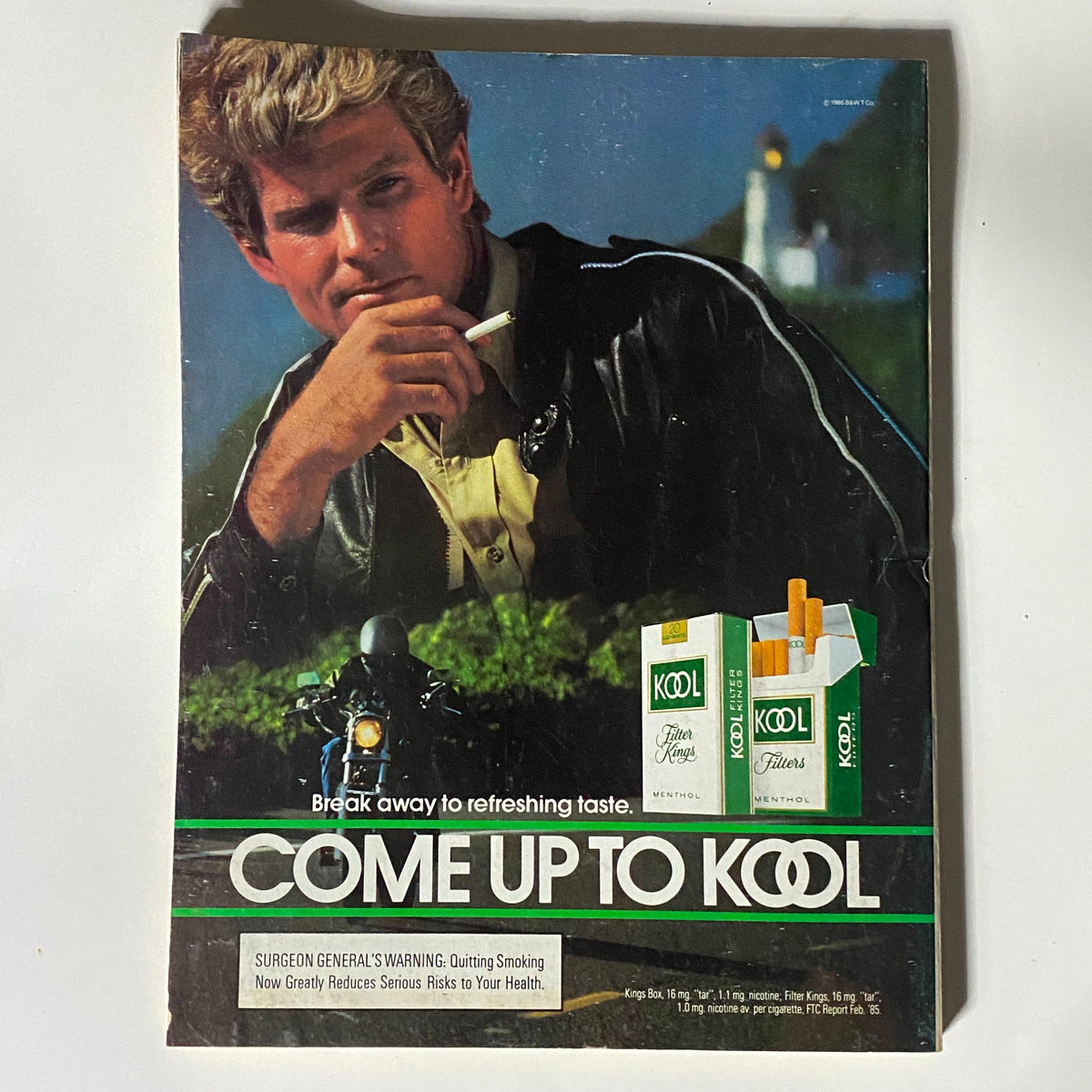 Vintage advertisement from the 1986 era, promoting Kool cigarettes with a model posing with a bike, encapsulating the 1980s style.