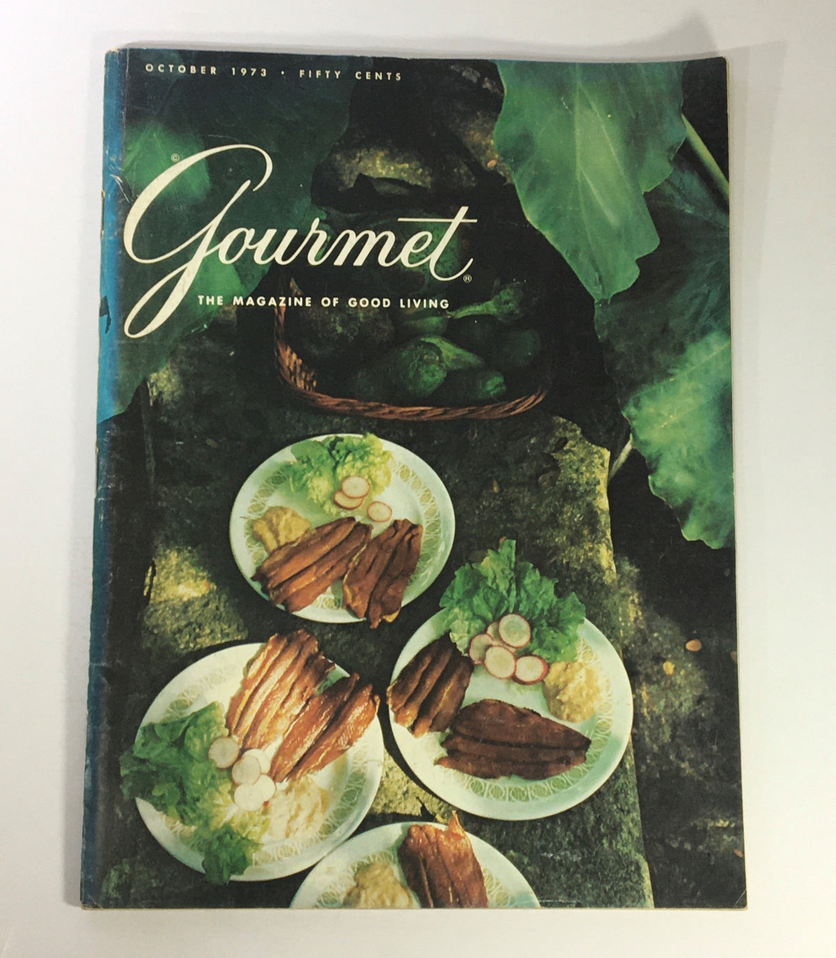 Cover of VTG Gourmet The Magazine of Good Living, October 1973 featuring a vibrant Caribbean meal with plates of food against a lush green background.