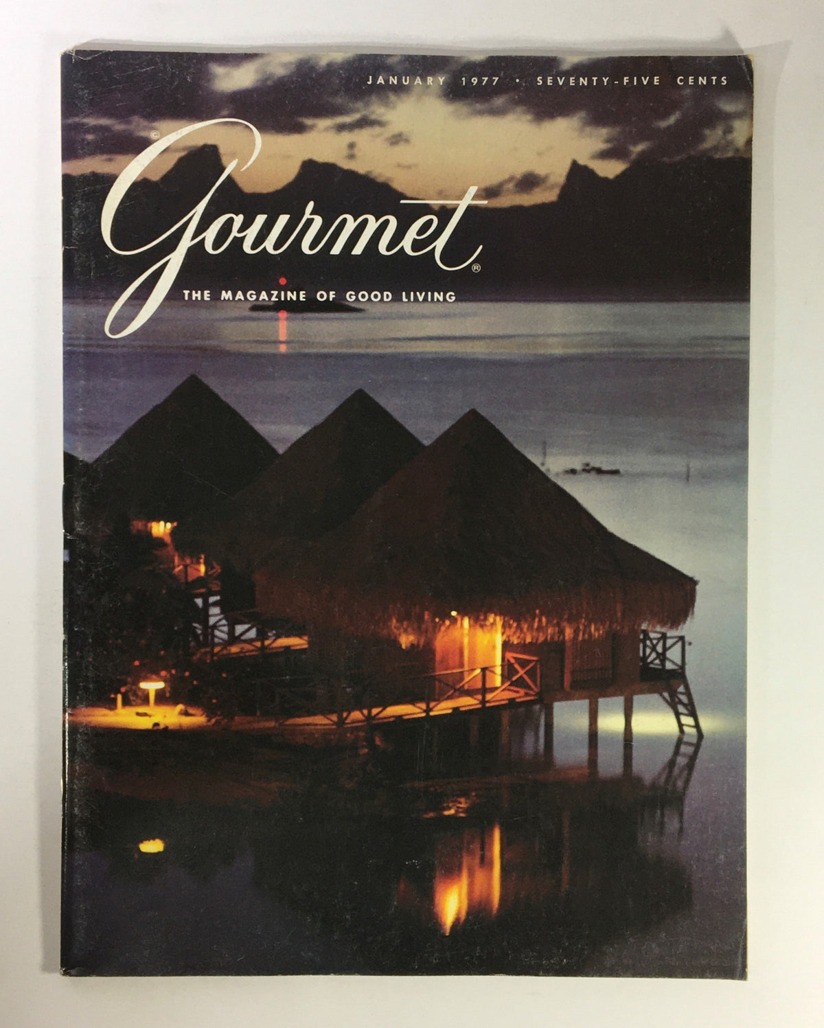 Cover of VTG Gourmet The Magazine of Good Living January 1977, showcasing beautiful waterfront huts illuminated at night, symbolizing French culinary culture and lifestyle.