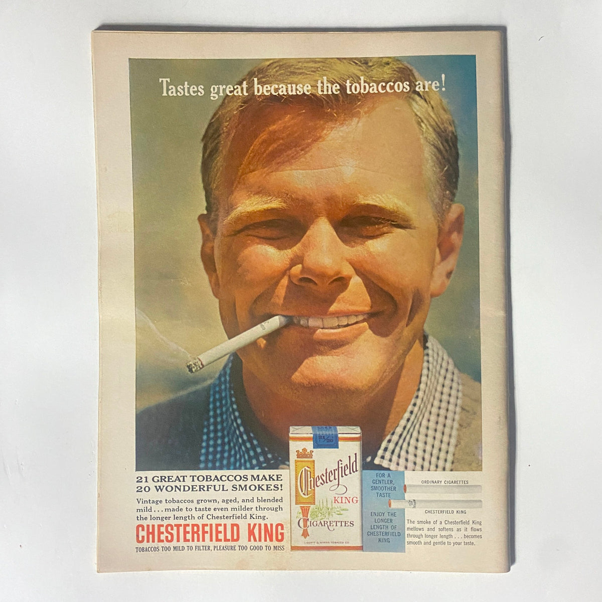 Vintage ad from the Motor Trend Magazine January 1963 featuring an image of a smiling man holding a Chesterfield King cigarette, promoting the brand with the tagline 'Tastes great because the tobaccos are!' This magazine represents the automotive scene of the early '60s, specifically highlighting the Charlotte National 400 race.