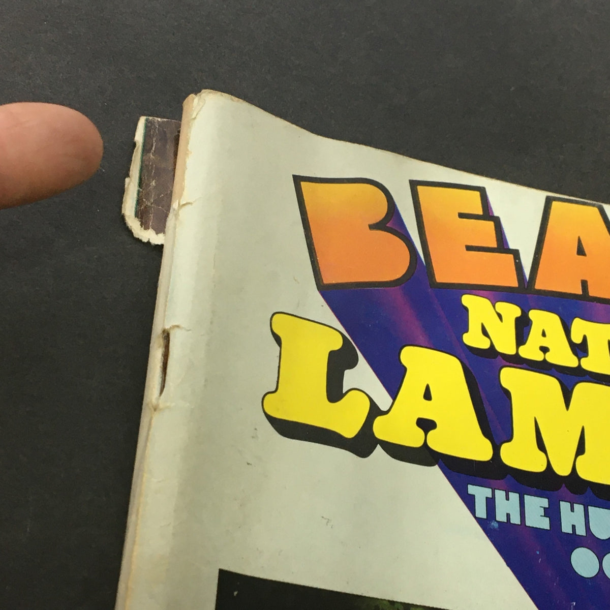 Close-up detail of The National Lampoon Humor Magazine October 1977 Edition featuring The Beatles, highlighting the wear on the magazine's spine, emphasizing its vintage authenticity.
