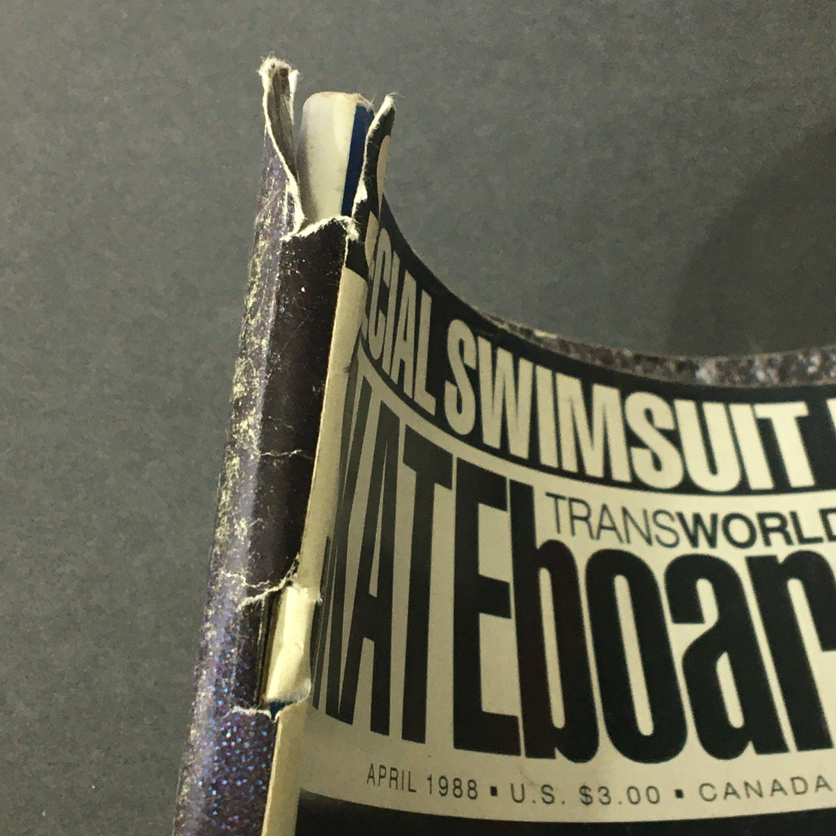 Close-up view of the spine of Transworld Skateboarding Magazine April 1988 - Special Swimsuit Issue showing minor wear and tear.