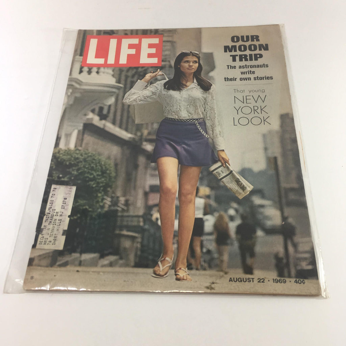 Cover of Life Magazine from August 22, 1969 titled 'Our Moon Trip: The Astronauts Write Their Own Stories'. The image features a model in a white blouse and purple skirt walking on a city street, symbolizing the trendy 1960s fashion amidst a backdrop of urban life.