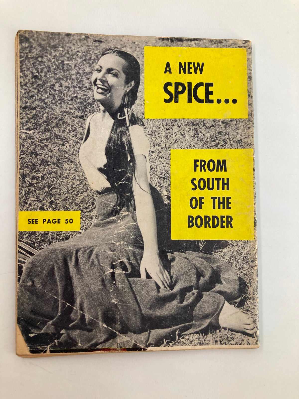 Back cover of Star Tabloid Magazine October 1954 Vol. 1 No. 1, featuring a smiling woman with the caption 'A New Spice... From South of the Border,' reflecting the magazine's diverse content.