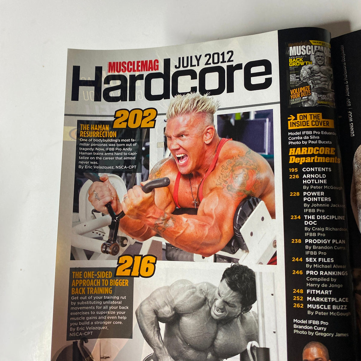 MuscleMag International Magazine July 2012 cover featuring intense bodybuilder training session. Highlights article topics such as back training and hybrid workouts for strength and muscle growth.