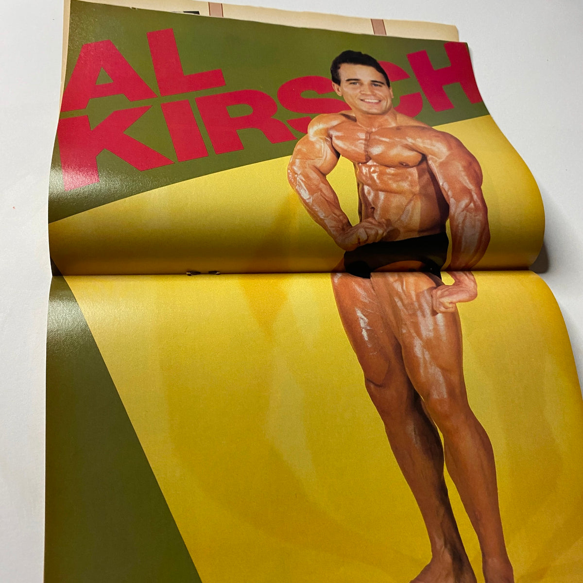 Centerfold of Al Kirsch from Muscular Development Magazine June 1985, displaying his impressive physique in a striking pose against a colorful background.