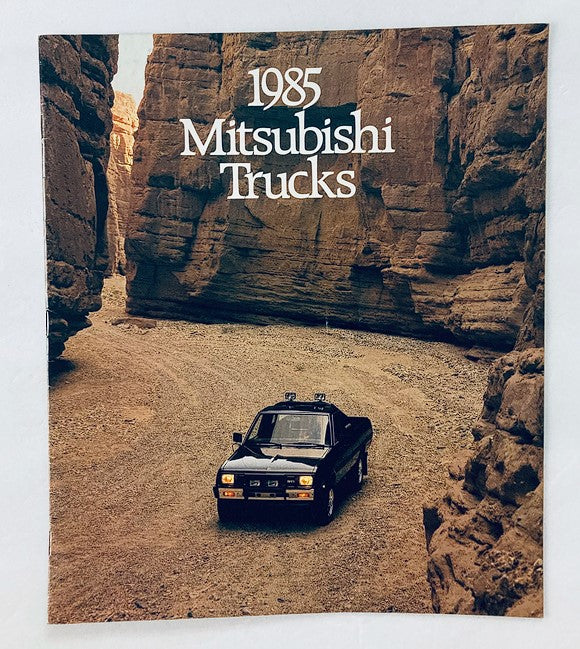 Cover of the 1985 Mitsubishi Trucks Dealer Showroom Sales Brochure showcasing a Mitsubishi truck driving through a scenic canyon.